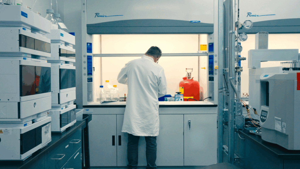 Lab professional working in a clinical laboratory environment supporting prescription dermatology formulation manufacturing.