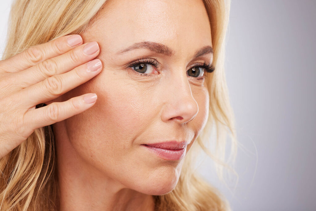 Mature woman examining skin on face - demonstrating skin health and estrogen-deficient skin concerns